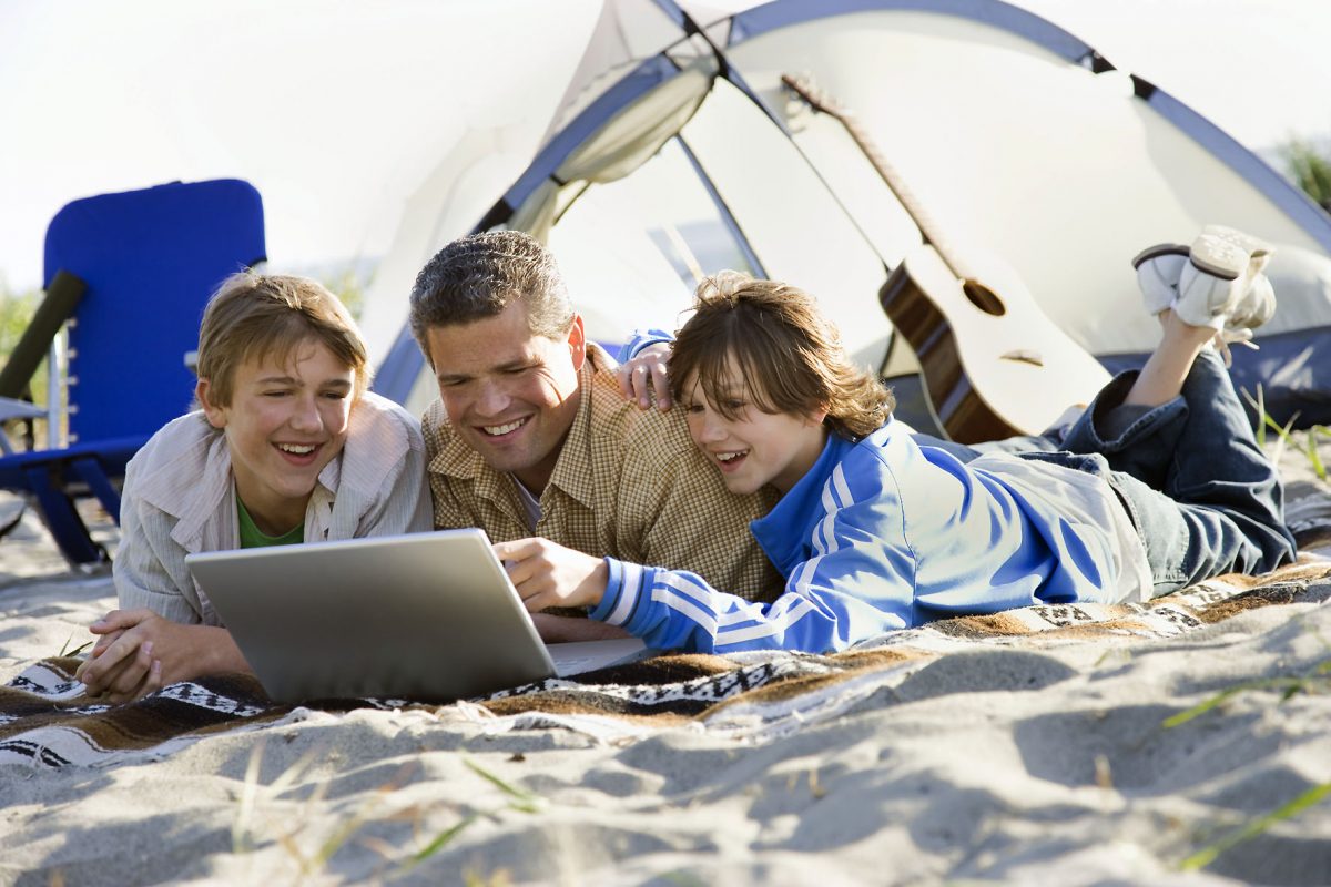 Father and Two Sons Using Laptop on Beach
